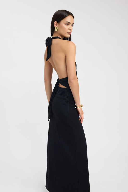 Side profile of black maxi dress showing fitted silhouette and flowing floor length design