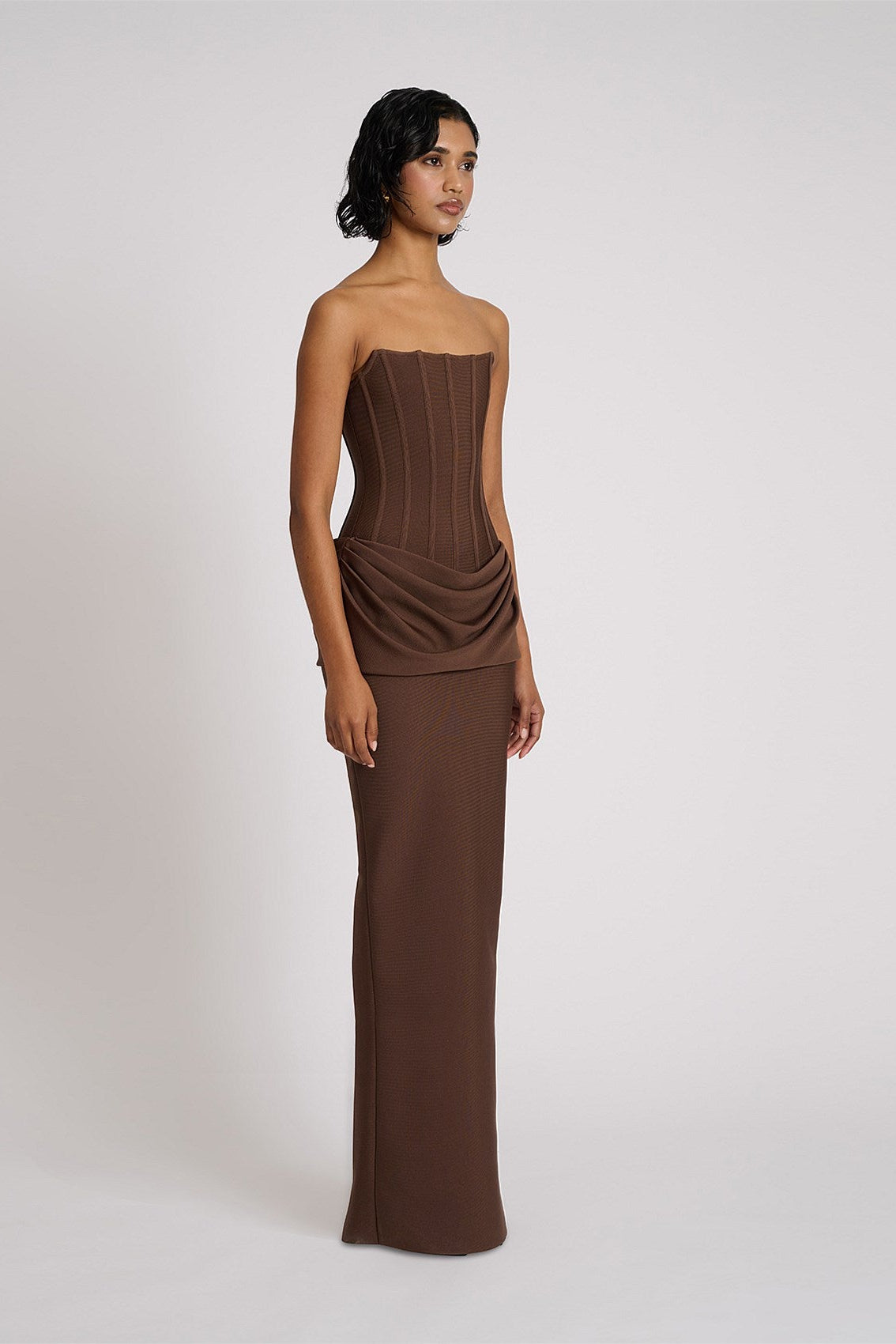 Side profile of chocolate brown gown showing fitted corset silhouette and elegant floor length drape