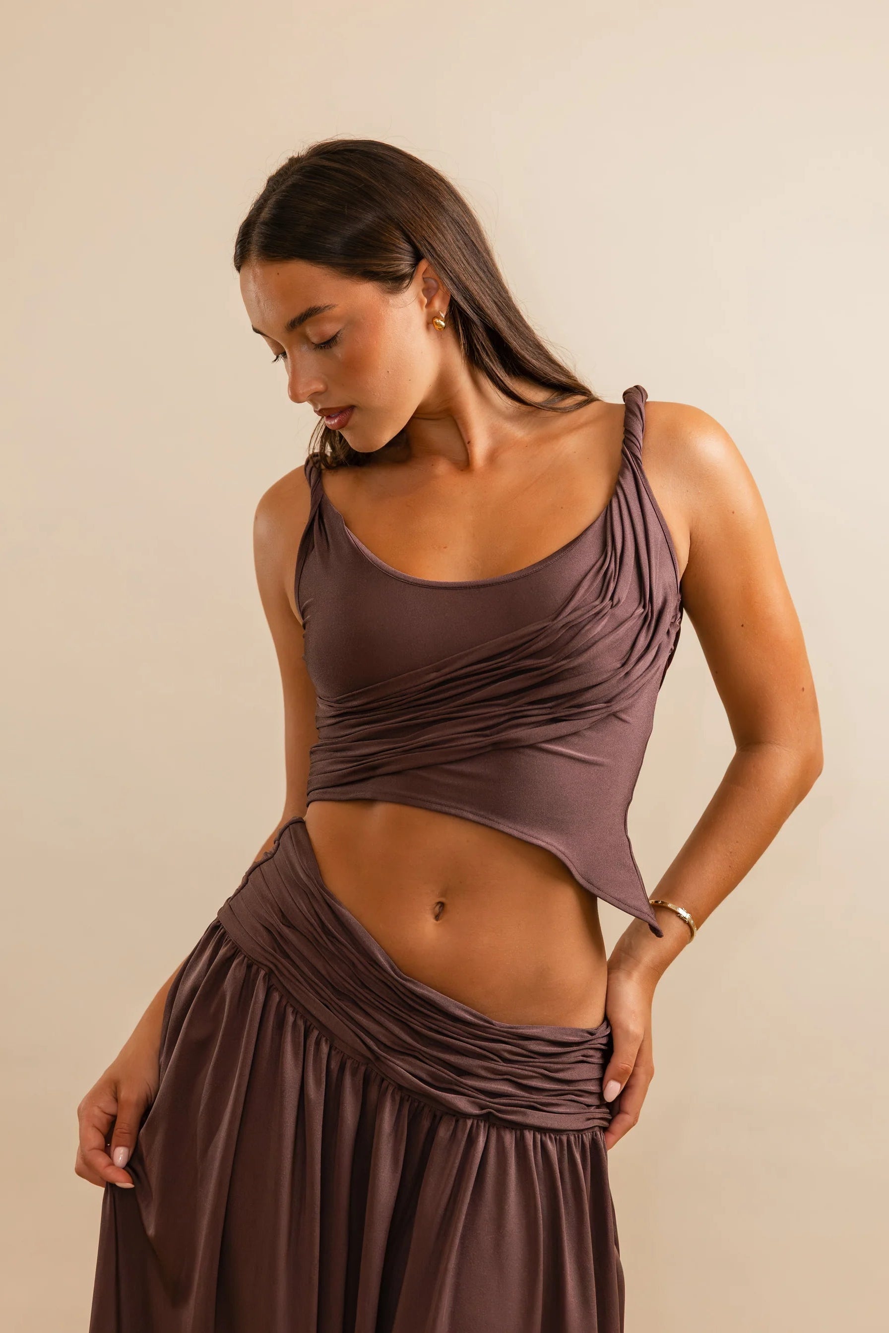 Close up of Calypso top in plum showing twisted straps and asymmetric draped hem with stretch fabric fit