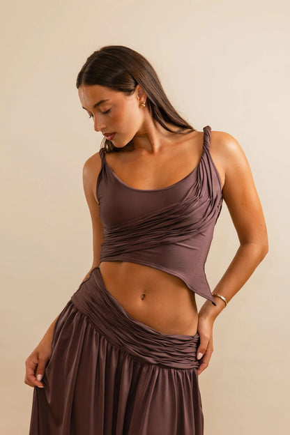 Close up of Calypso top in plum showing twisted straps and asymmetric draped hem with stretch fabric fit