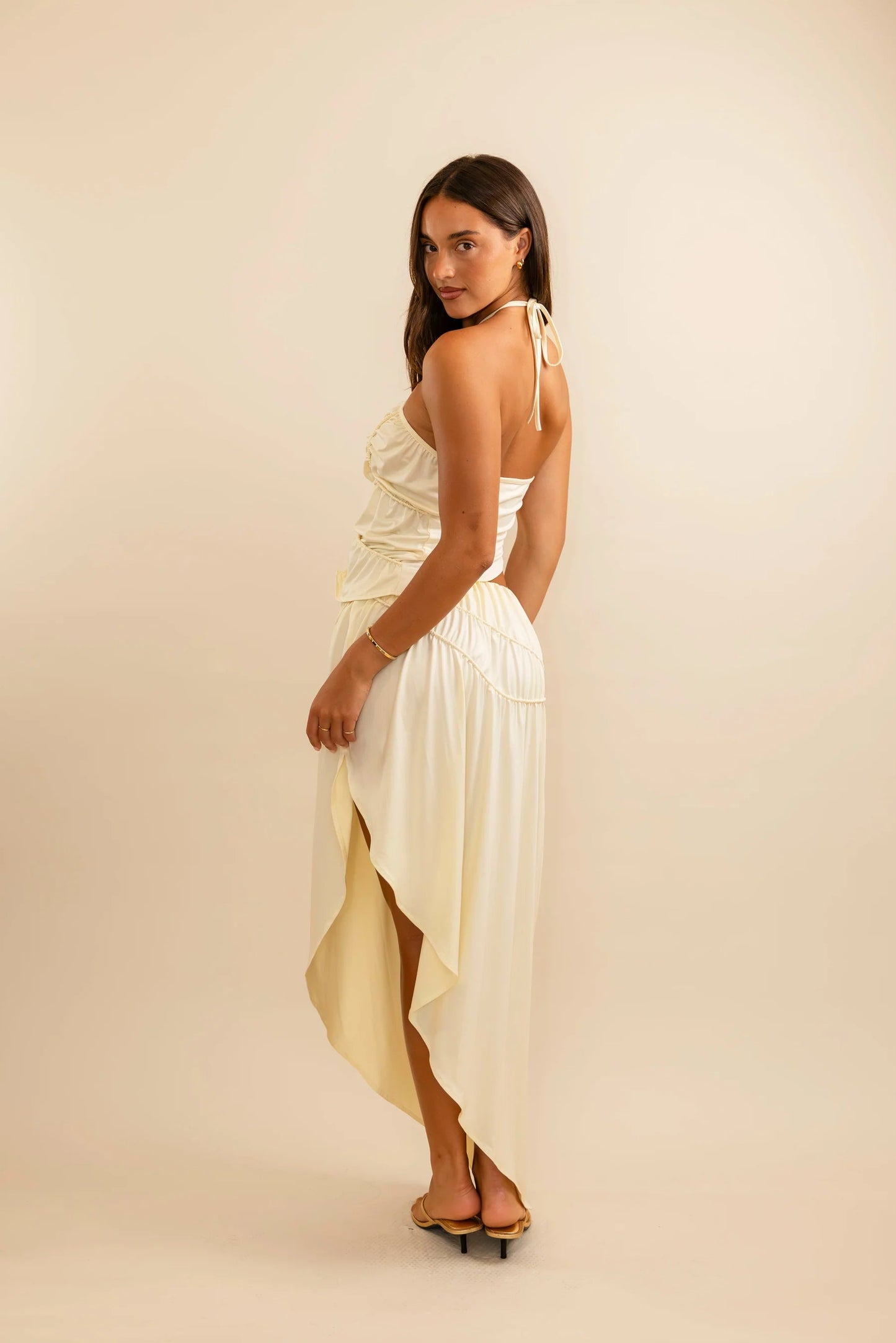Cream asymmetrical skirt with side slit detail and sculpted piping across the waist for a flattering feminine silhouette