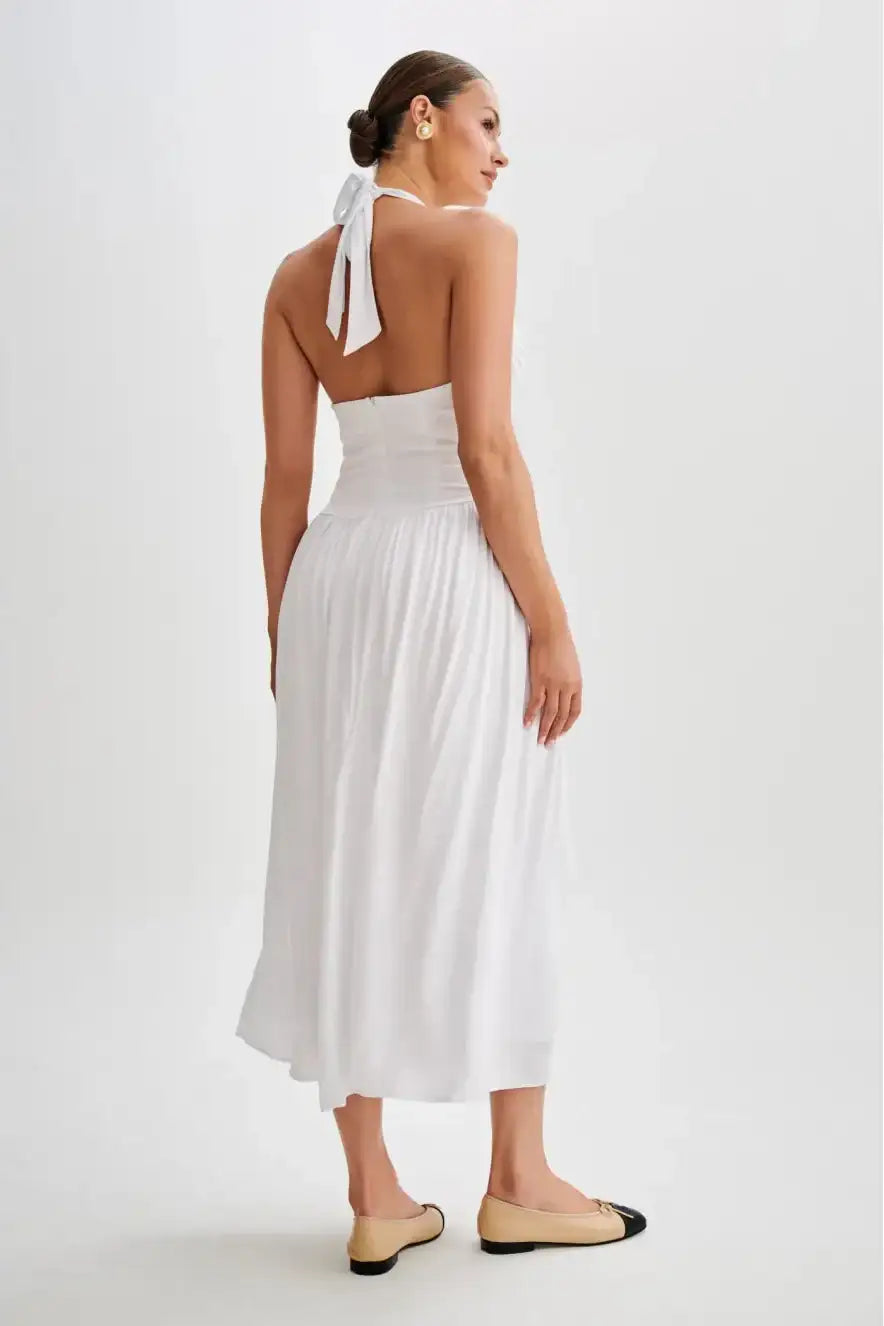Back view of white halter midi dress featuring open back design, halter neckline and smooth fitted waist with flowing skirt