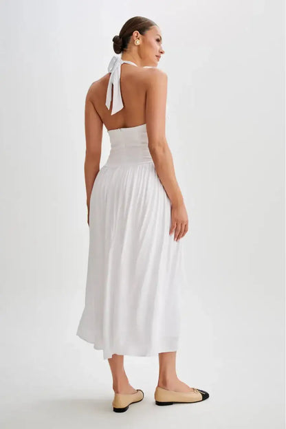 Back view of white halter midi dress featuring open back design, halter neckline and smooth fitted waist with flowing skirt