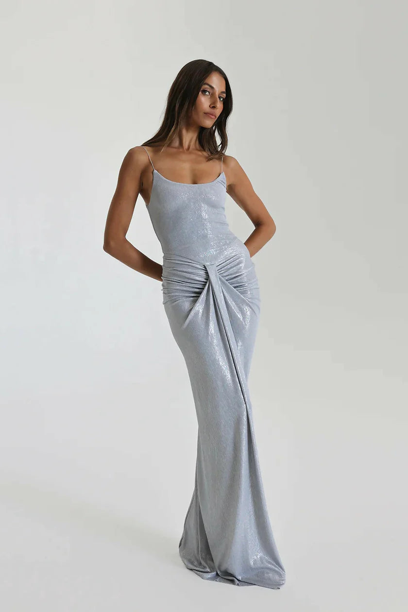 Natalie Rolt Allora Gown in silver featuring stretch metallic fabric, scooped neckline, draped waterfall detailing and elegant floor length silhouette with soft fluid finish