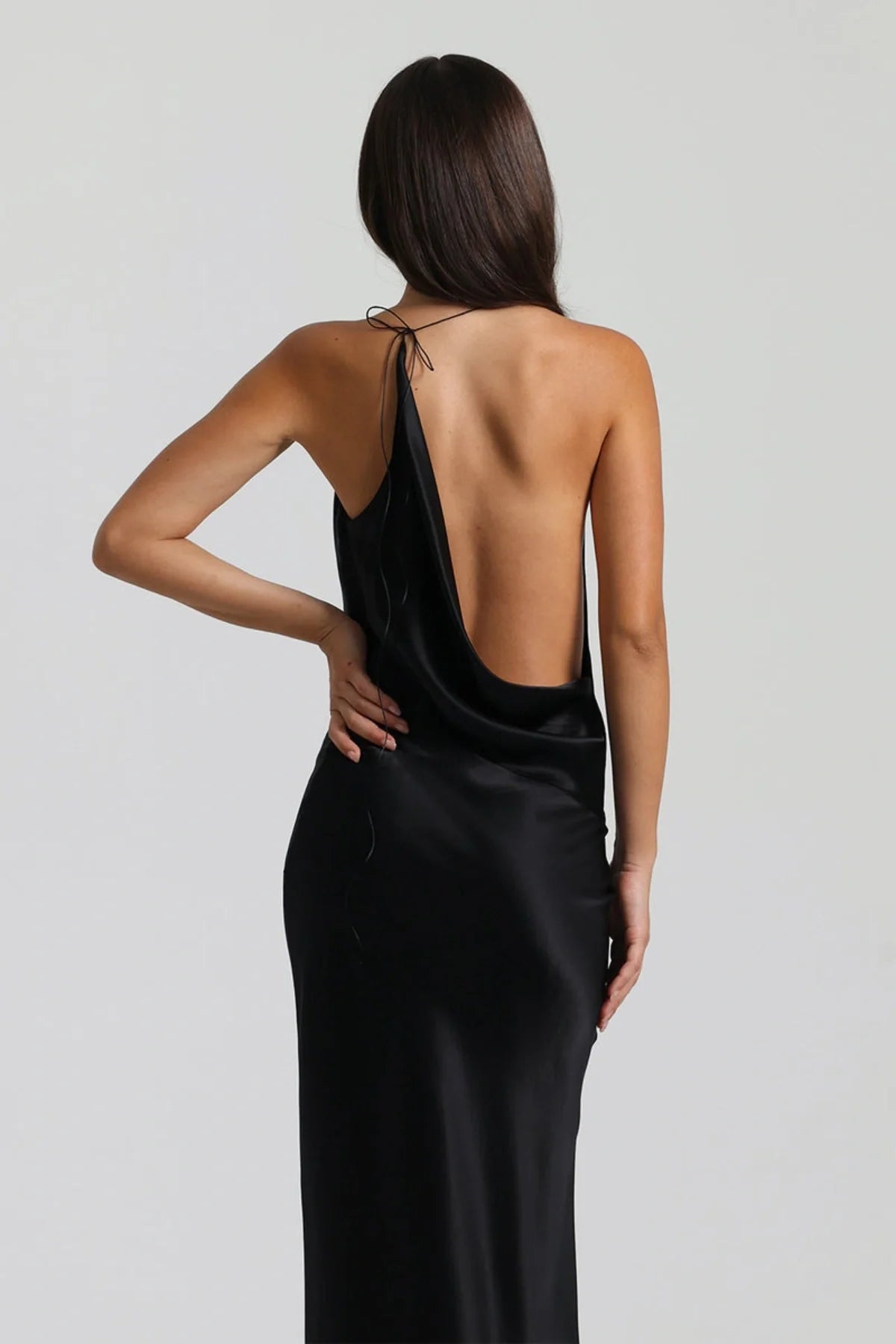 Back view of black silk gown featuring open back design and low drape detail with smooth elegant finish