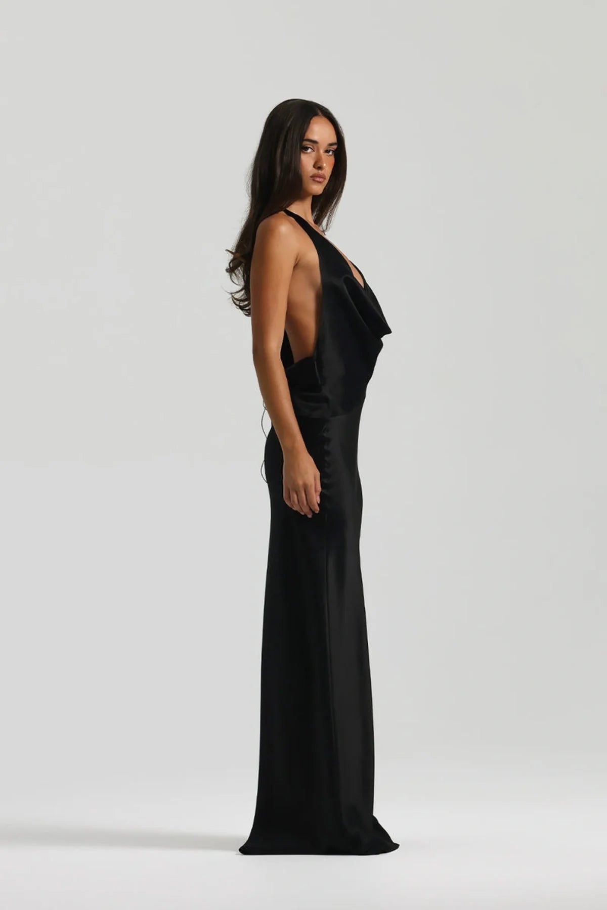 Side profile of Natalie Rolt Gabi Gown in black showing elegant bias cut silhouette and flowing floor length drape
