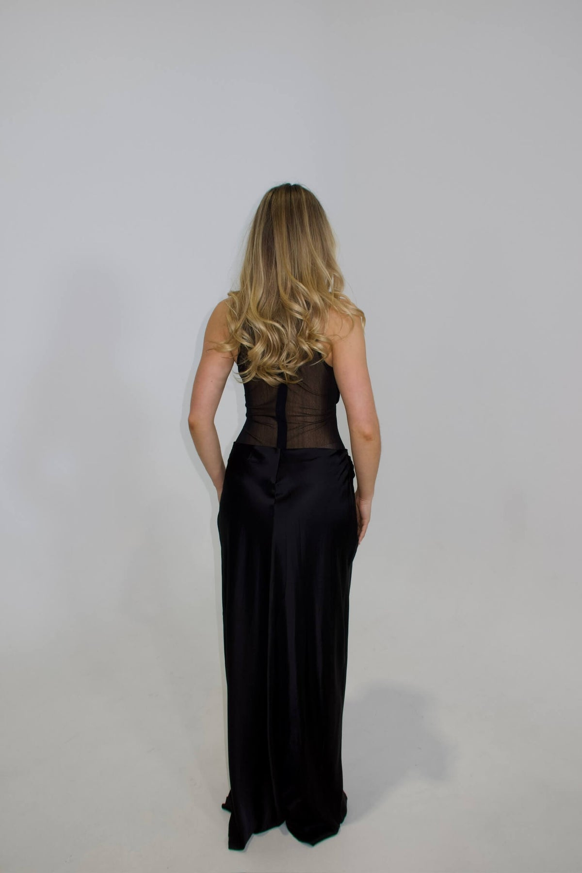 Back view of NBD Fiza Maxi Dress in black showing the fitted silhouette and back neckline