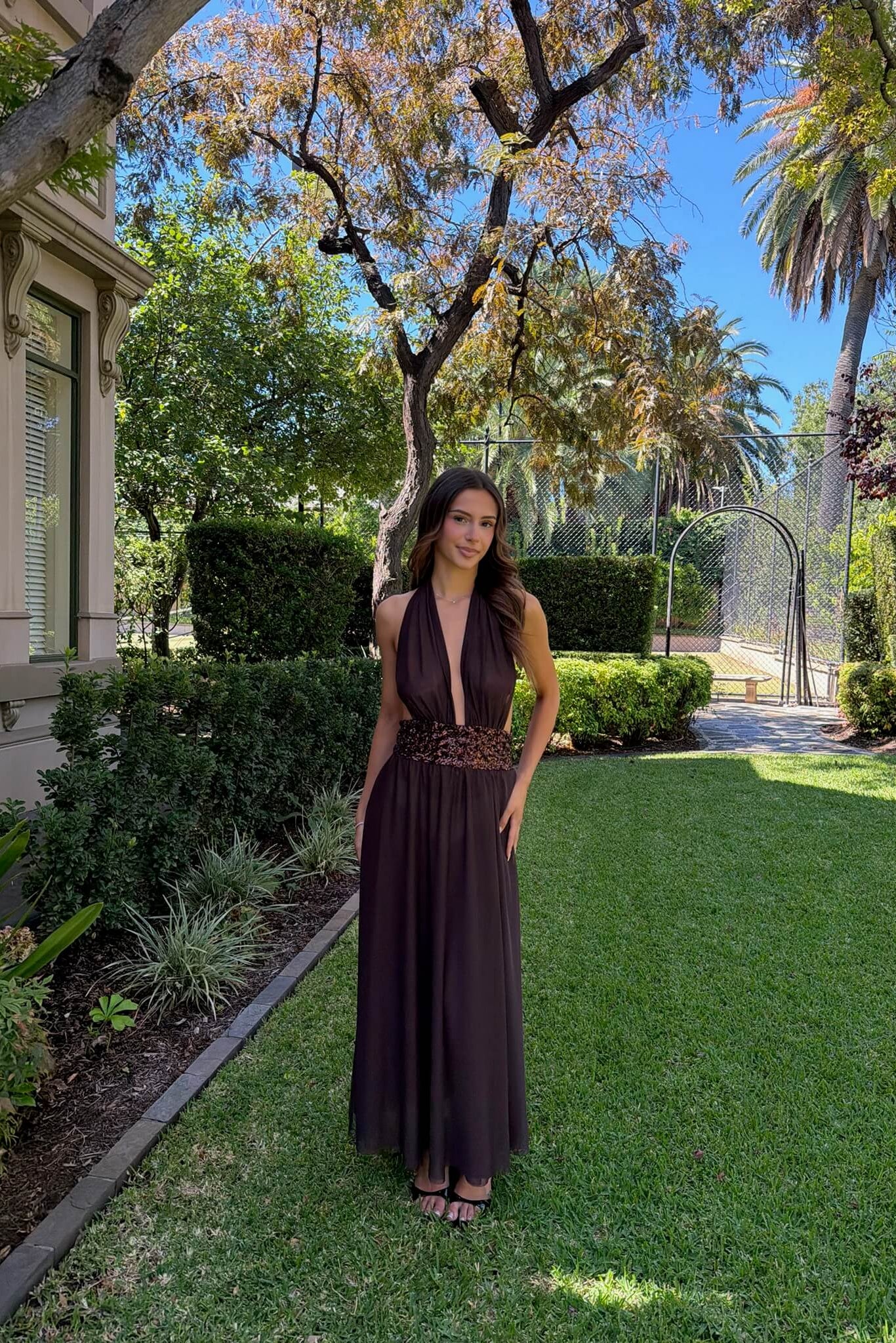 Far shot of the Saboa Studios Alessandra Maxi Dress in brown highlighting the neckline, bodice and premium fabric detail