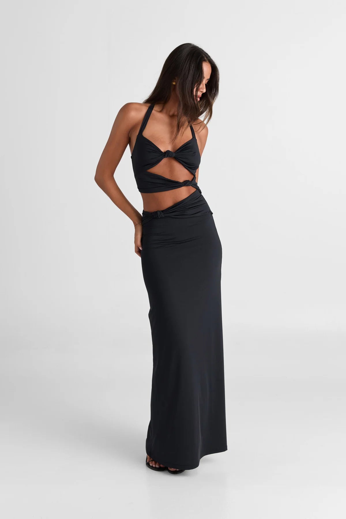 Black maxi dress with halter neck design, front twist detail and waist cut-outs creating a modern fitted silhouette