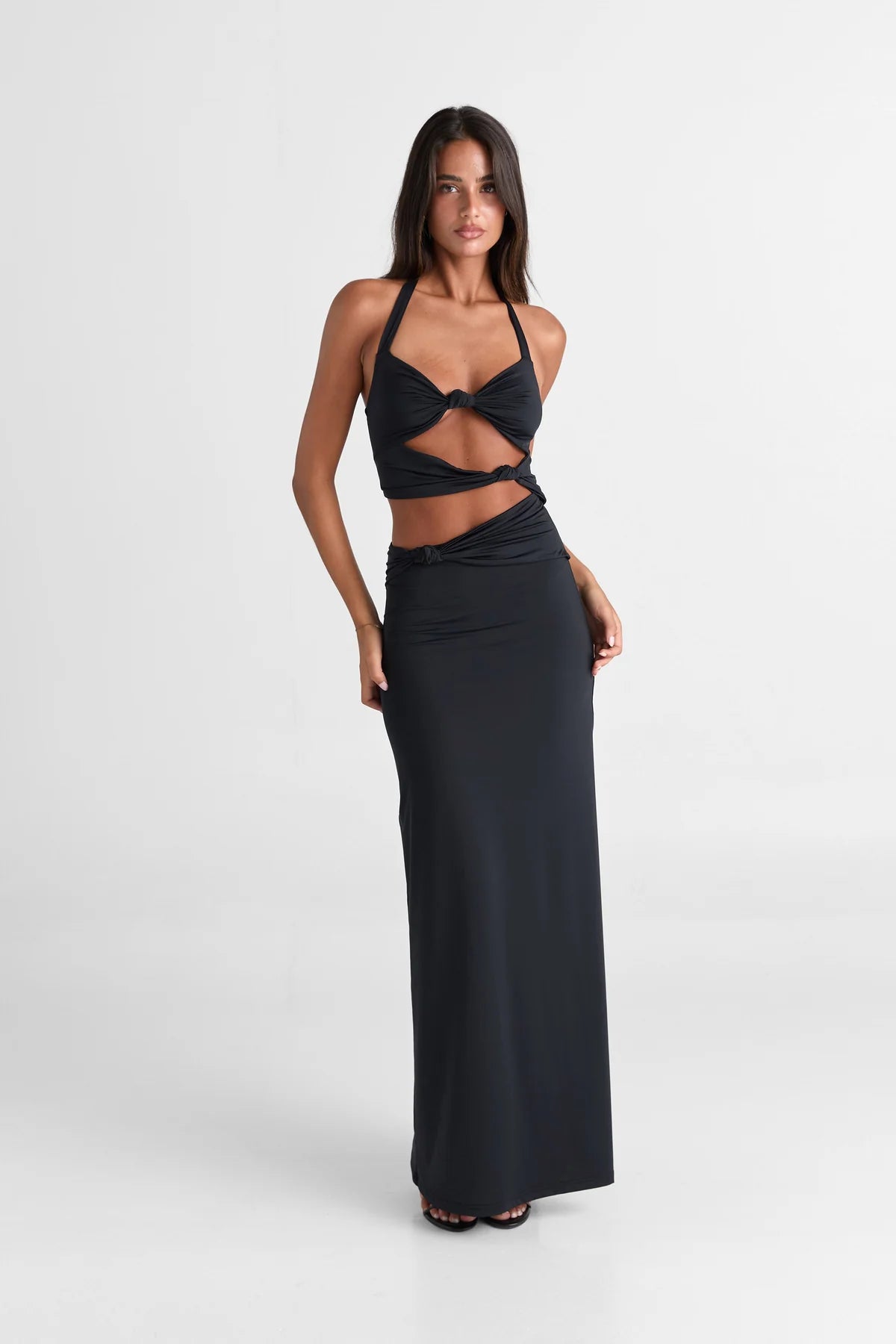 Sasha Therese Oralia Maxi Dress in black featuring halter neckline, twist front bust detail and elegant floor length silhouette with soft stretch jersey fabric