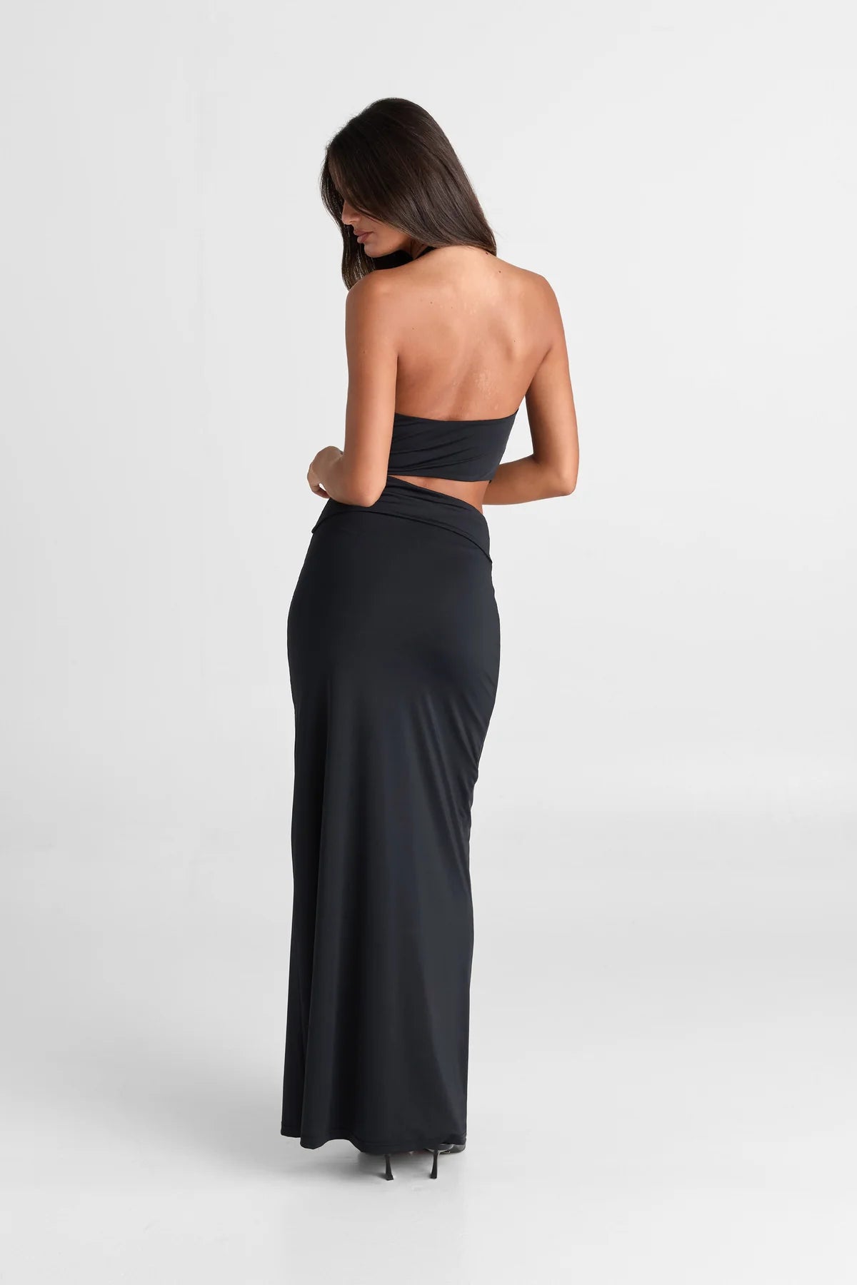 Close detail of waist cut-outs on black maxi dress showing fitted shaping and body contouring jersey fabric