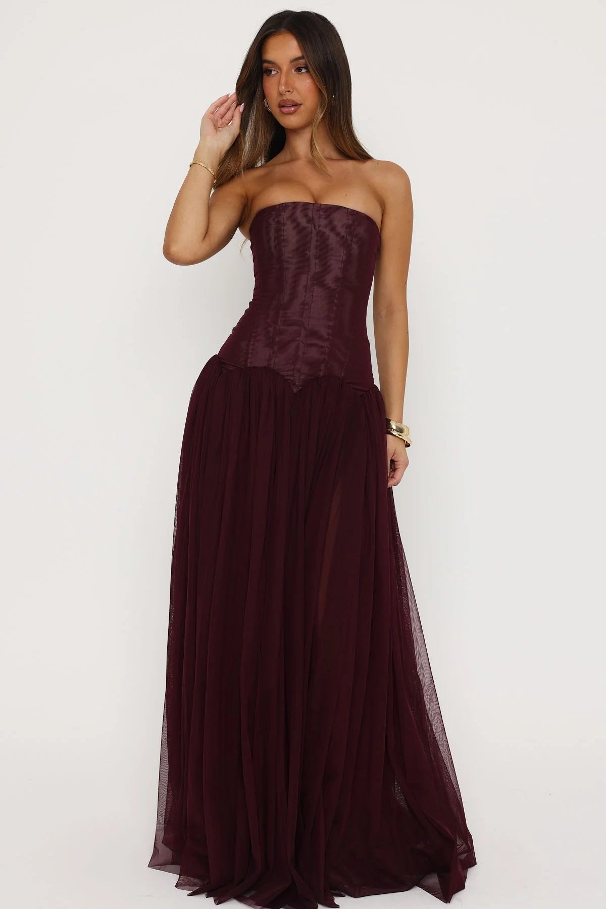 Elegant fig coloured formal maxi dress styled for wedding guest or formal occasion with strapless corset design