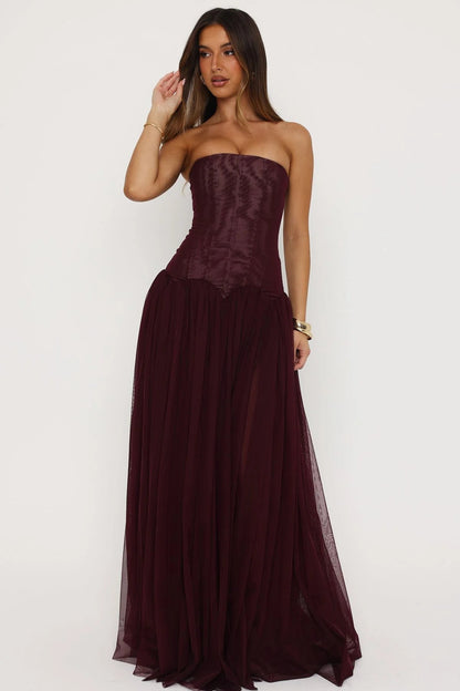 Elegant fig coloured formal maxi dress styled for wedding guest or formal occasion with strapless corset design